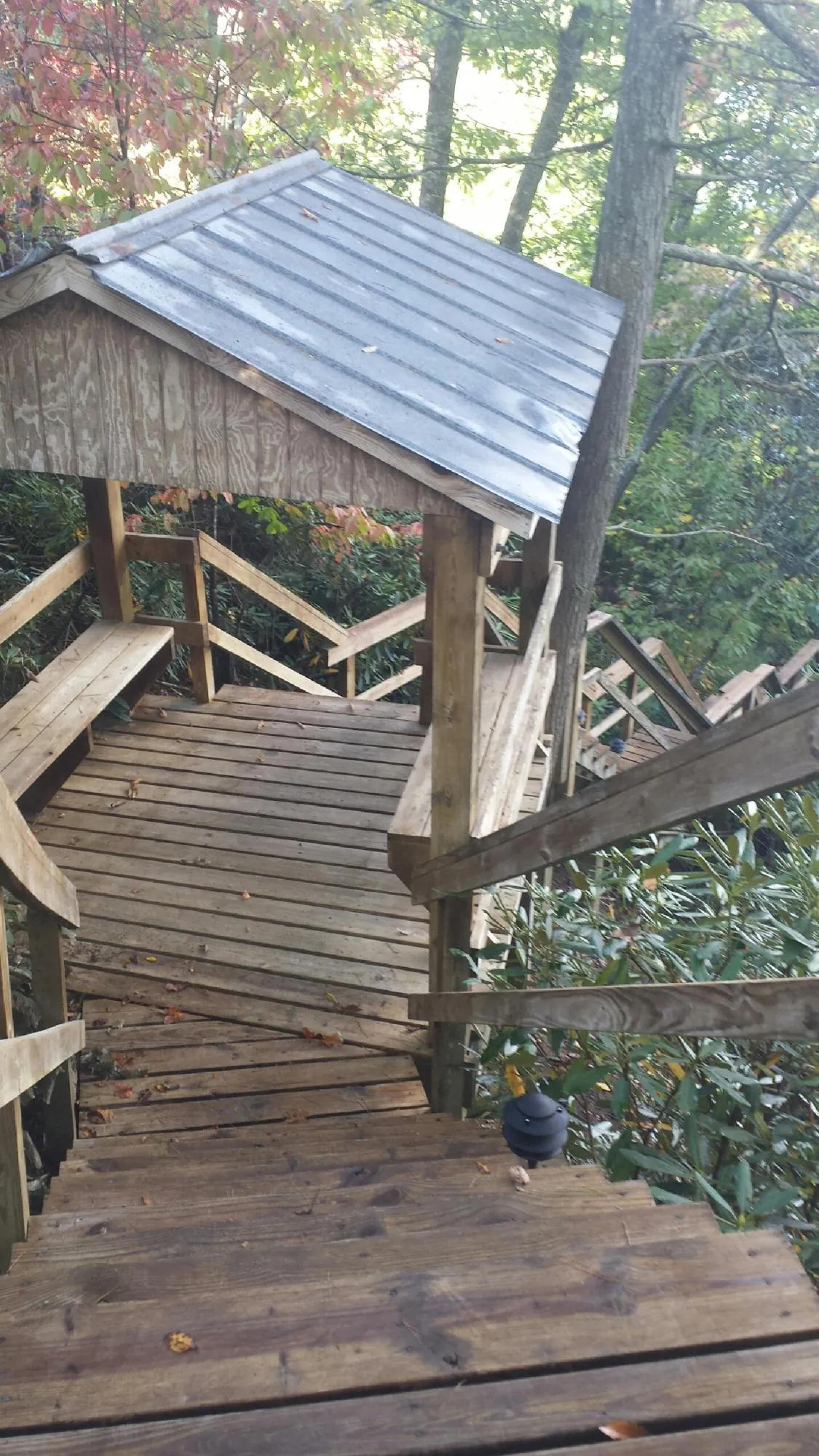 Metal roofed shelter over wooden steps on a wooded walkway — Skylight Repair & Installation work by our crew in Manitowoc