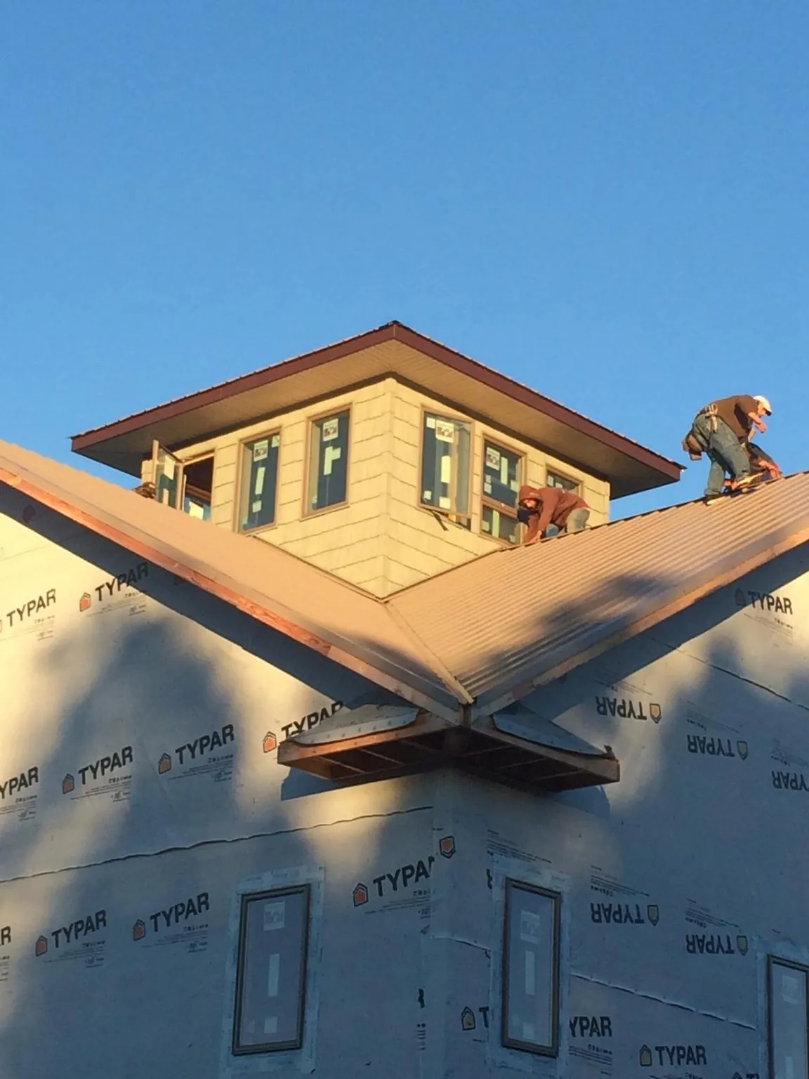 Roofers working around a rooftop cupola on a new metal roof at sunset — Roof Waterproofing in Manitowoc by Roofing Brothers